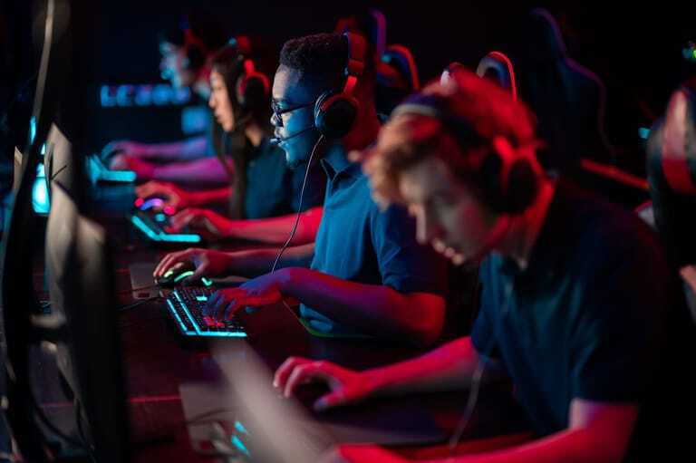 Junge Menschen spielen Computerspiele im Neonlicht.